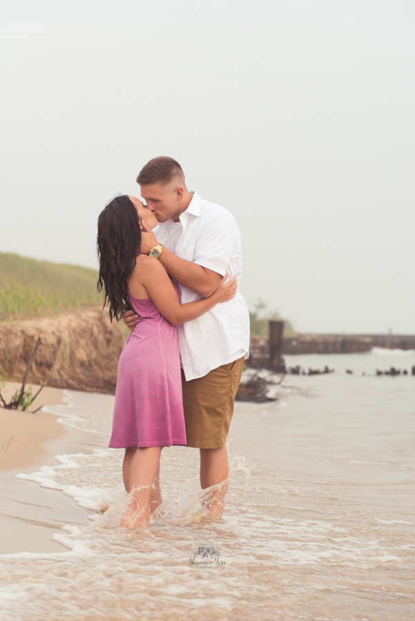 Engagement Photography in Ludington MI of couple standing on beach kissing