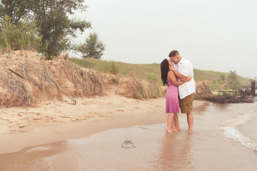 Engagement Photography in Ludington MI of couple standing on beach kissing