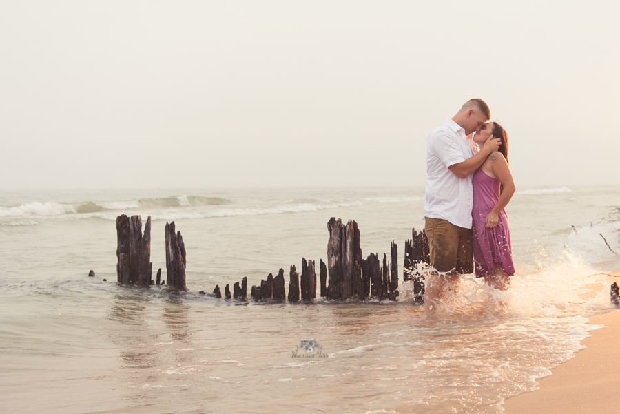 Engagement Photography in Ludington MI of couple standing on beach kissing 