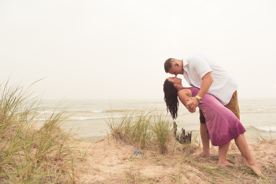 Engagement Photography in Ludington MI of couple dipping on sand dunes 