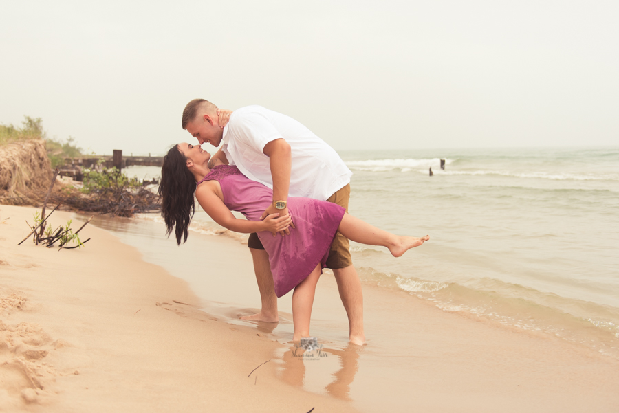 Engagement Photography in Ludington MI of couple dipping on beach