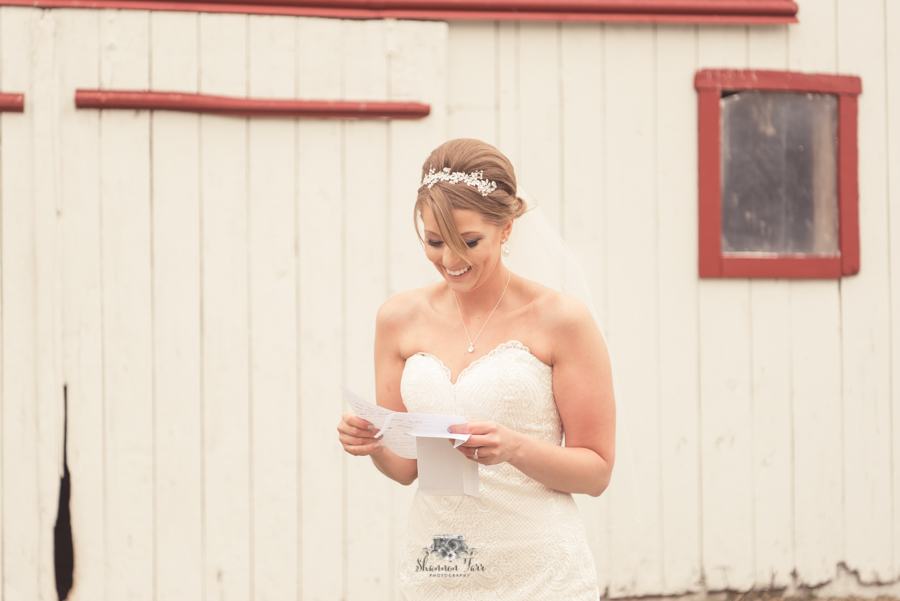 Bride reading letter from groom by barn
