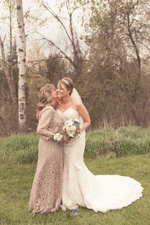 Mother kissing daughter on wedding day