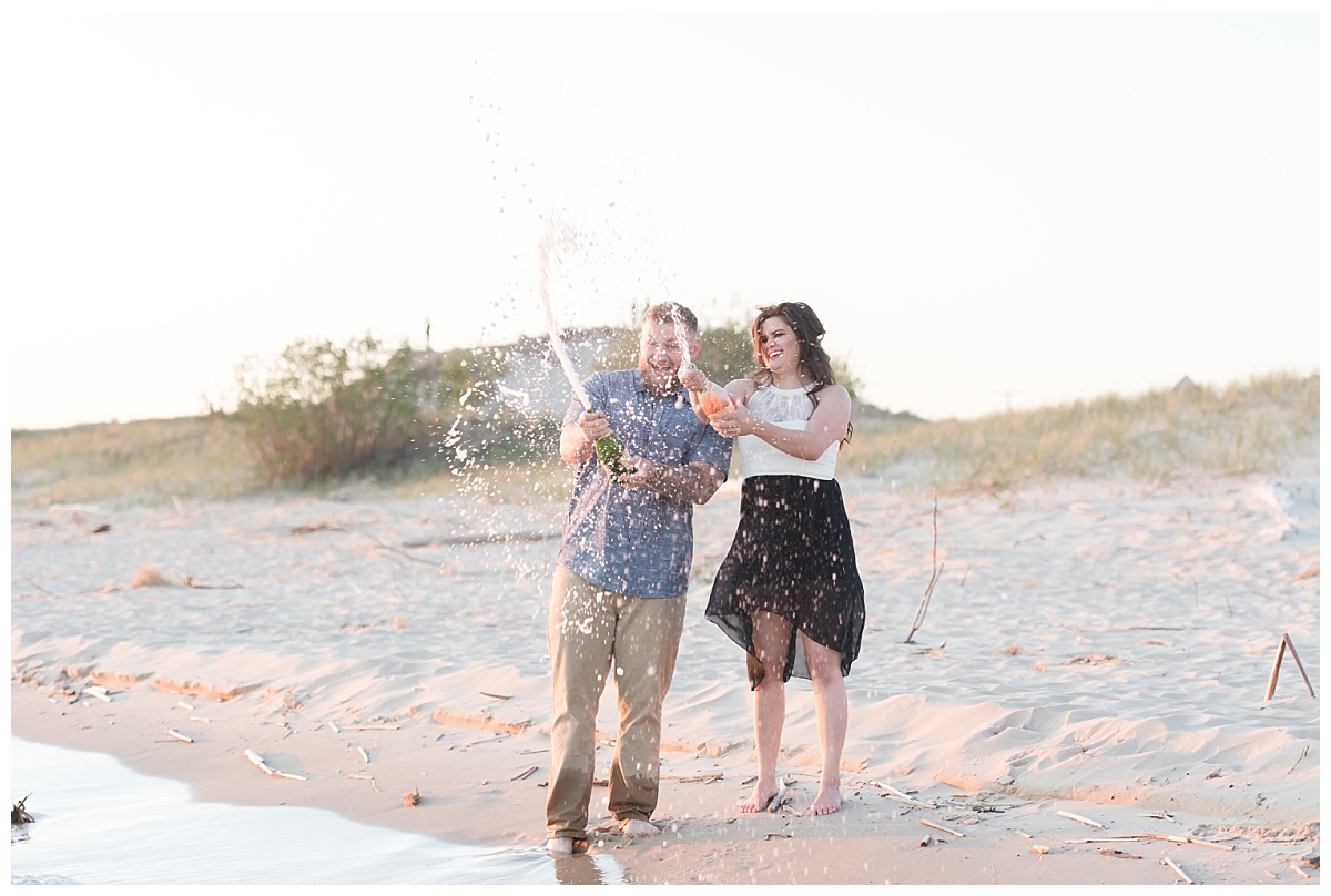 couple standing on beach opening champagne