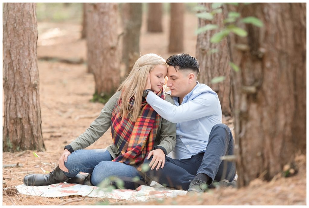 couple sitting on blanket in forest snuggling