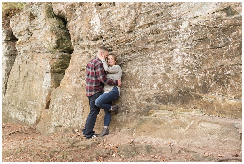 couple standing next to rock wall whispering to each other