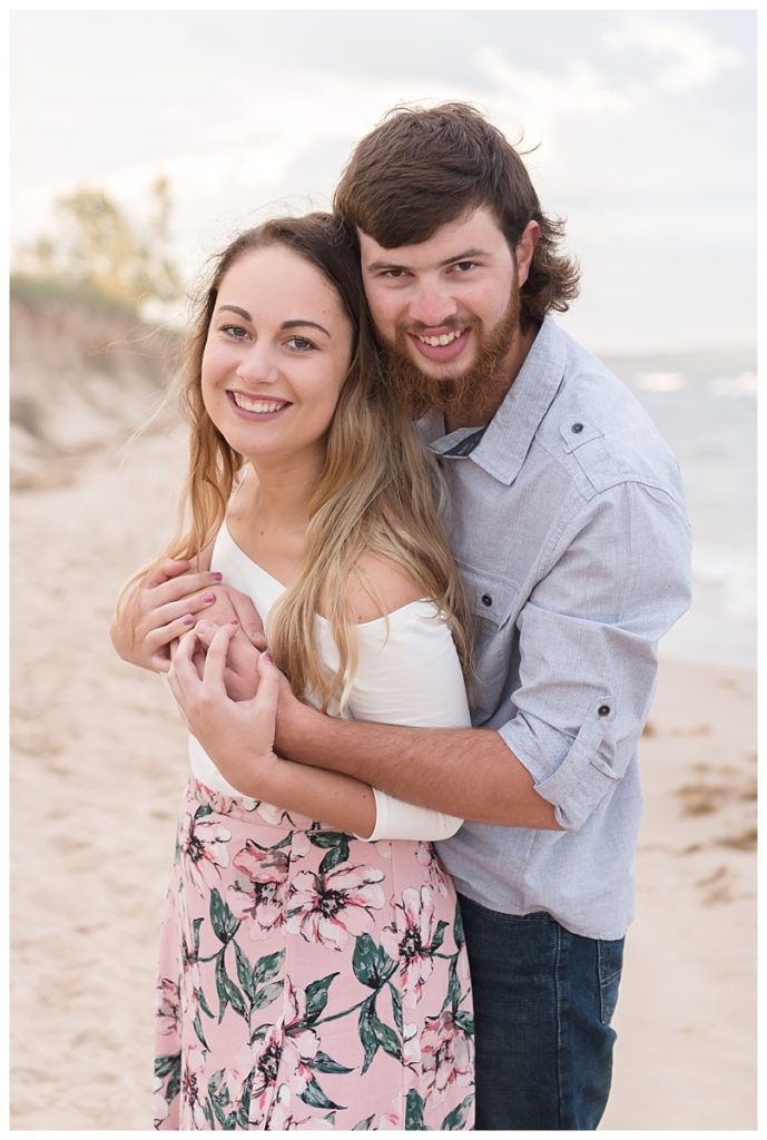 couple standing on beach holding each other