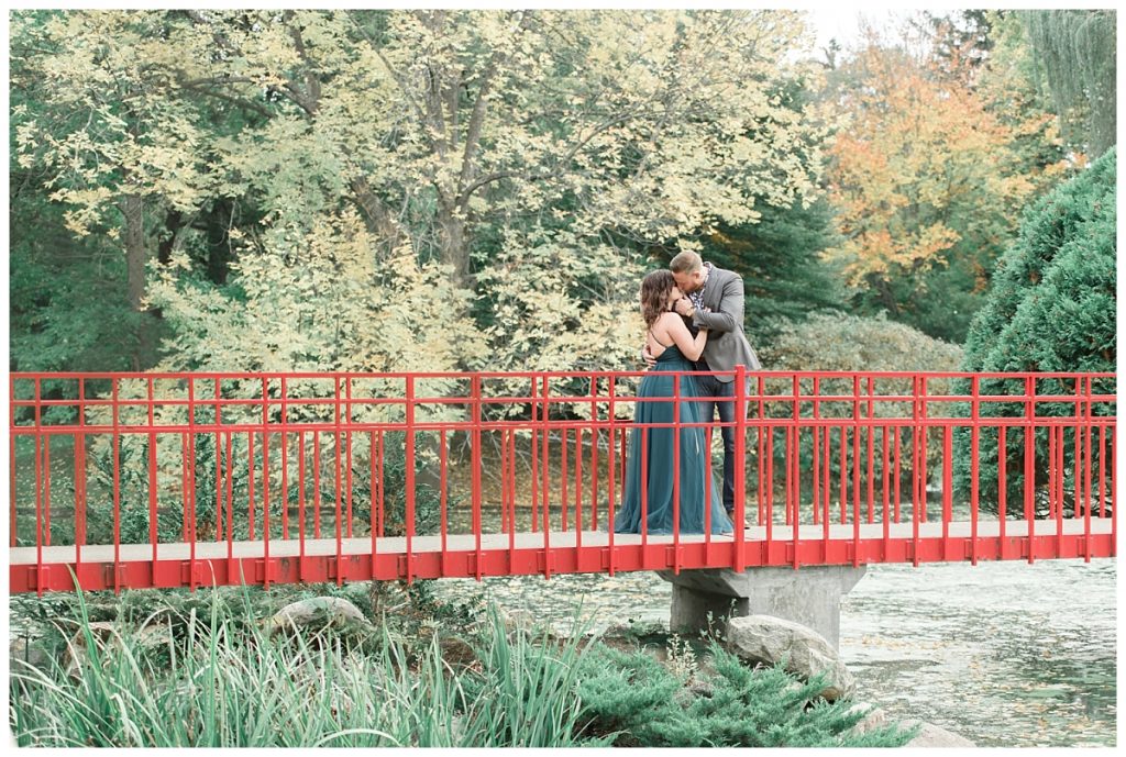 couple standing on red bridge at Dow Gardens