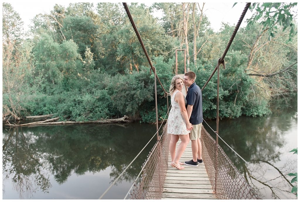 couple standing on foot bridge over river